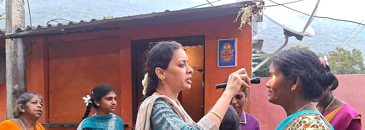 A doctor examining a patient's eyes at a rural home visit